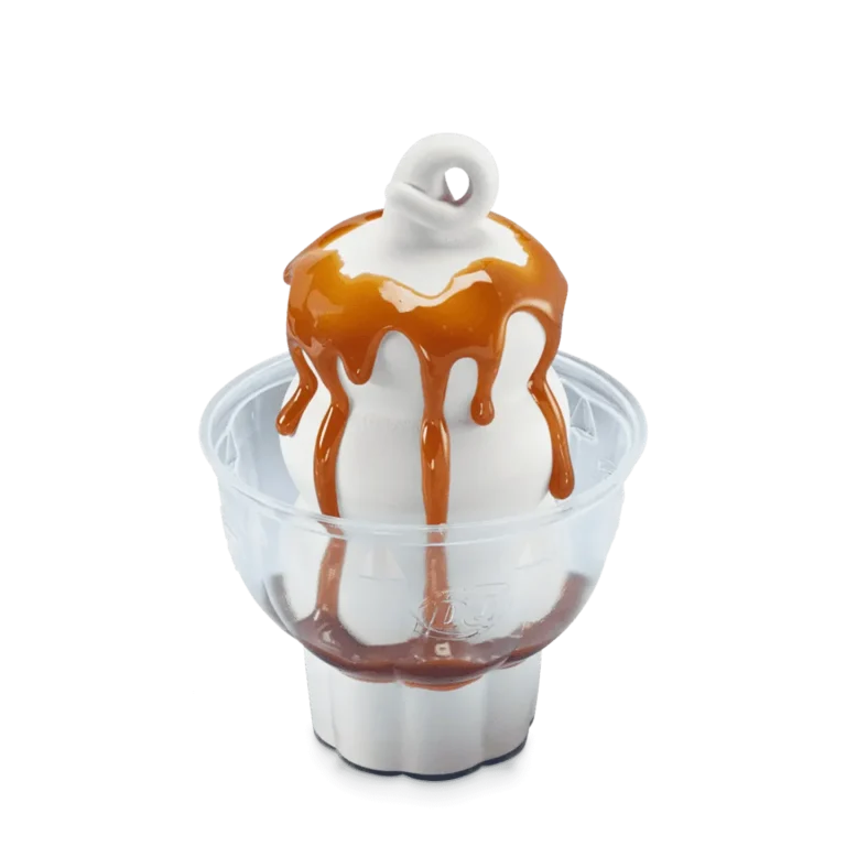 vanilla soft serve sundae topped with caramel sauce in a white cup