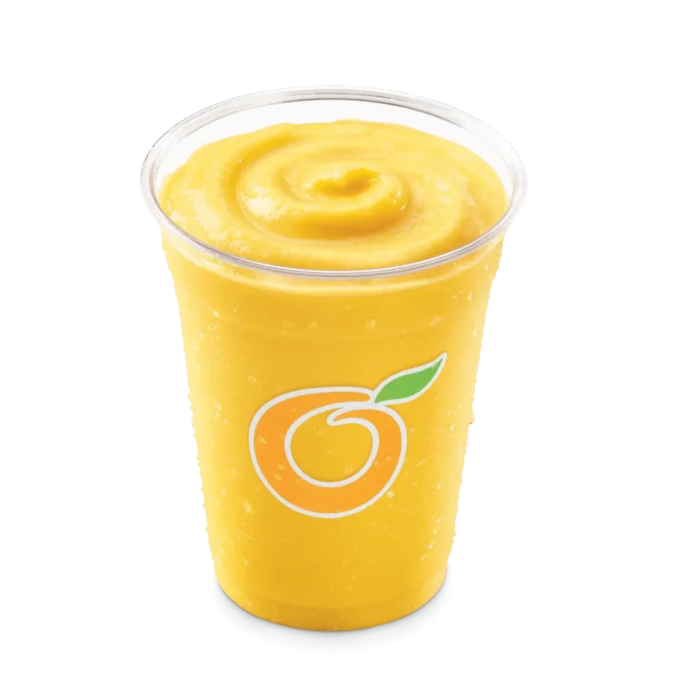 Tall clear cup filled with yellow mango pineapple fruit smoothie with a straw